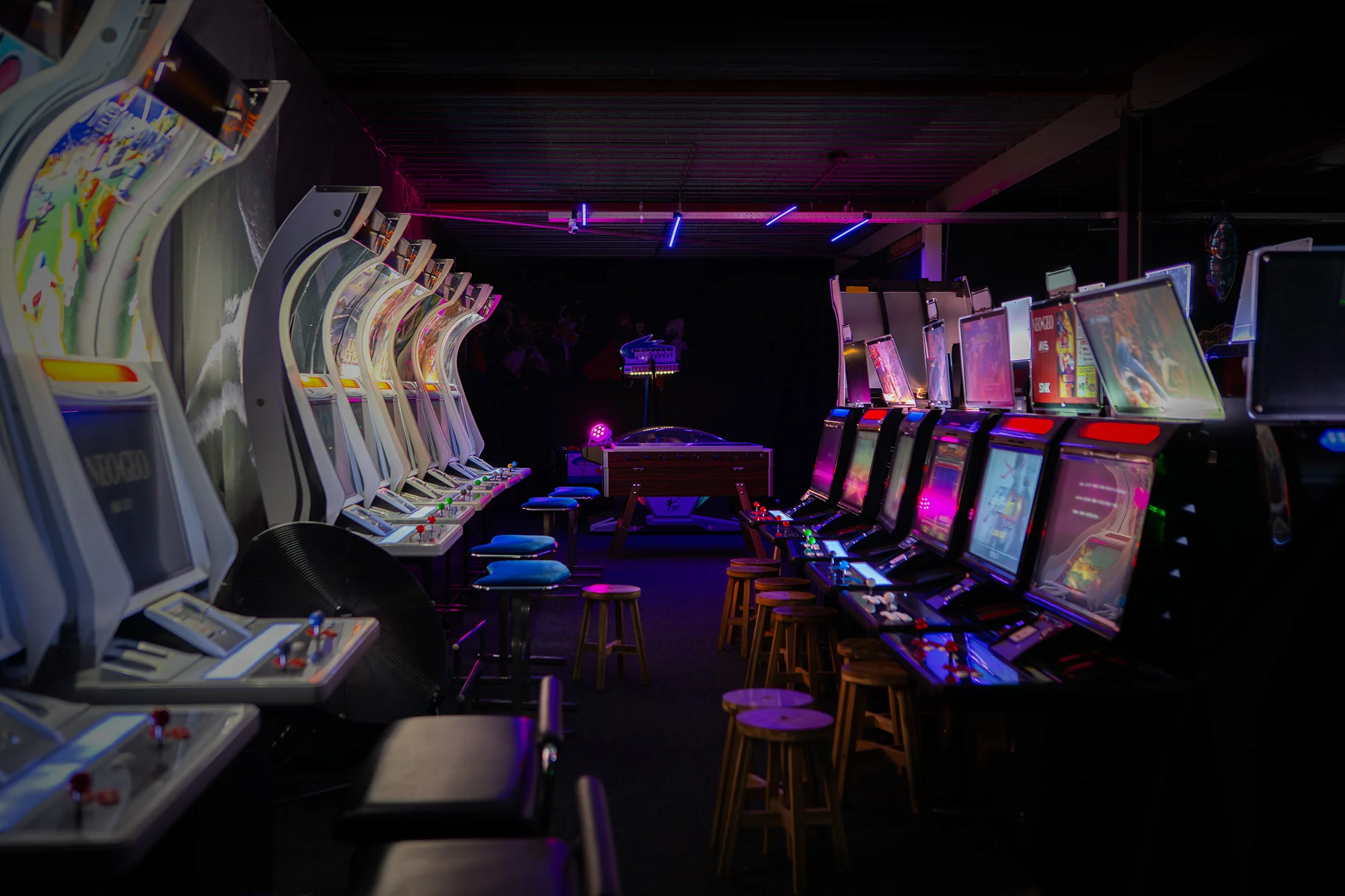 An aisle of Japanese arcade cabinets lit in purple and pink at Blast Galaxy