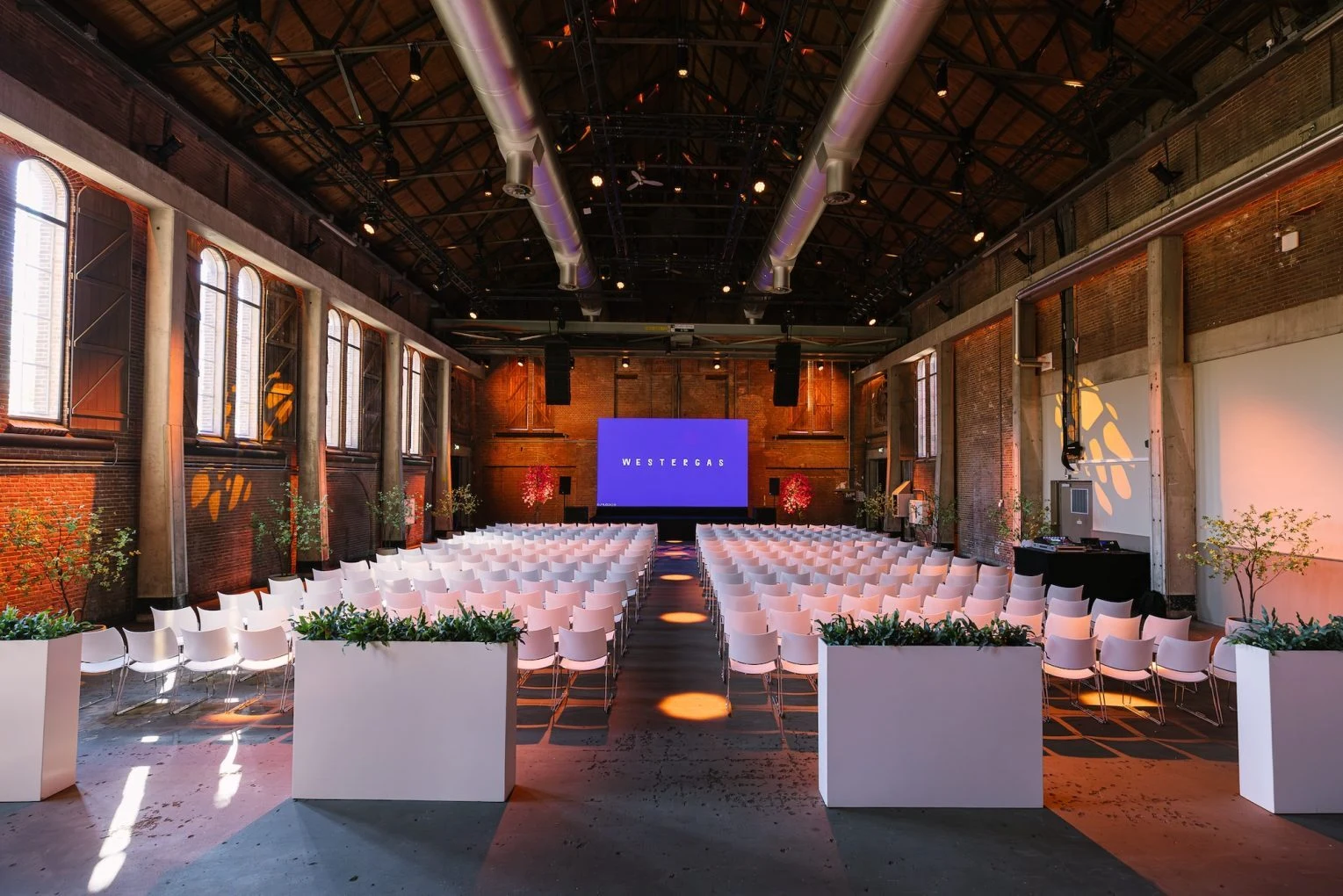 The Transformatorhuis hall at De Wester, Amsterdam, set with conference seating facing a stage screen